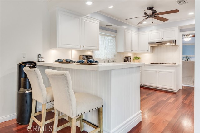 Kitchen with a coastal inspiration offers breakfast bar, white shaker cabinets, stainless appliances and hardwood floors