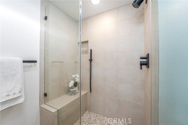 Walk-in shower in primary bath with bench, hand shower and shower head.