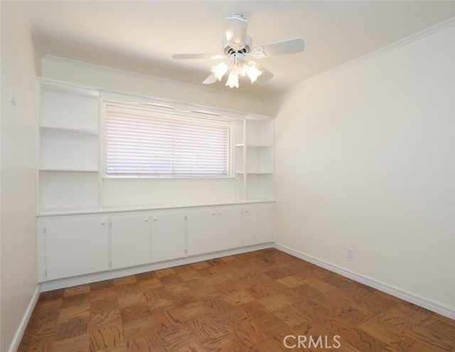 Bedroom 2 with extensive built-ins, refinished wood floor and ceiling fan.