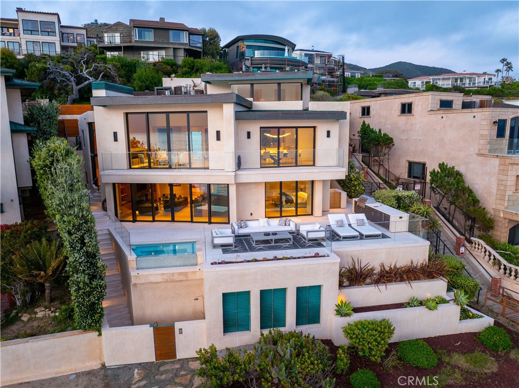 This is more than just a home; it’s a lifestyle. Your dream coastal retreat is a stunning contemporary estate nestled on pristine sands in Lagunita, one of a few gated beachfront communities in Laguna Beach. This magical setting features 270-degree panoramic ocean views encompassing Catalina Island in front, the Montage on the left, and Victoria Beach on the right. Whales nuzzle against the boulders in the center of your view, an incredible glimpse of the natural world at your doorstep. Designed by esteemed architect Stephen Thompson and renowned builder Tony Valentine, this residence represents the pinnacle of craftsmanship and style, where every detail reflects a commitment to quality and excellence. 

Ground up remodel in 2018, the home offers 6,738 sq ft of luxurious living space across four levels, meticulously crafted for both grand entertaining and intimate gatherings. The 54 feet of beachfront allow you to relish the serenity; outdoor living space offers direct community steps, beach access, on-deck infinity spa, Lynx grill, and al fresco kitchen. Expansive interior features four en-suite bedrooms, office, and a total of eight beautifully appointed bathrooms. Design details include four custom fireplaces swathed in onyx & marble, plus a one-of-a-kind stone mantel embedded with fossils. Nearly 12-foot-high ceiling in living room, unique among beachfront homes, add to the sense of space and drama. 

Dedicated entertaining space features a custom semicircular movie theater with unparalleled acoustics, billiard room with seated bar, 420-bottle wine cellar, video game room & bathroom, gym, locker room and steam/sauna. Gourmet kitchen is equipped with top-of-the-line Miele and Viking appliances with a bulthaup hood fan. Elevator serves all four levels and three-bay garage, a rarity in this exclusive area. This is truly the ultimate in Laguna Beach luxury — and it’s waiting for you.