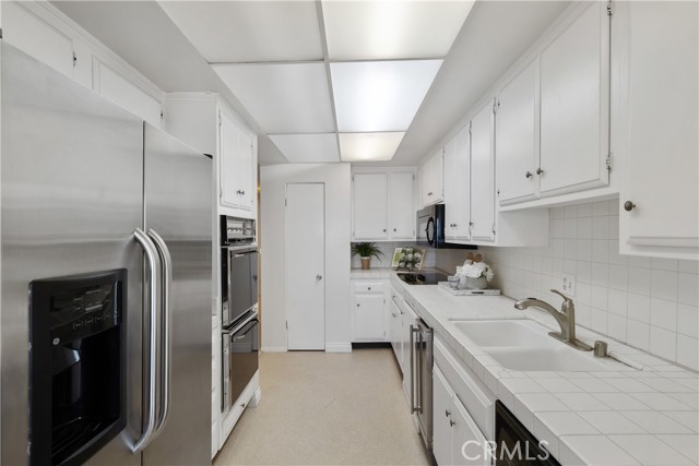 The kitchen is appointed with refrigerator, range, dual-ovens, microwave, dishwasher, wine refrigerator, white cabinetry, ample storage and large panty.