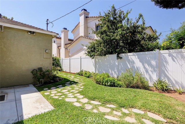 Charming walk path from the outdoor dining patio to the rear yard.