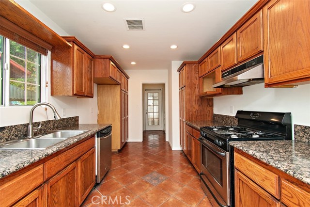 Large Galley Kitchen with granite counter tops, plenty of cherrywood cabinets for storage, spanish tile flooring