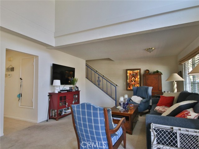 Another photo of the living room showing stairs and the entry to the kitchen, dining area and family room on the left.