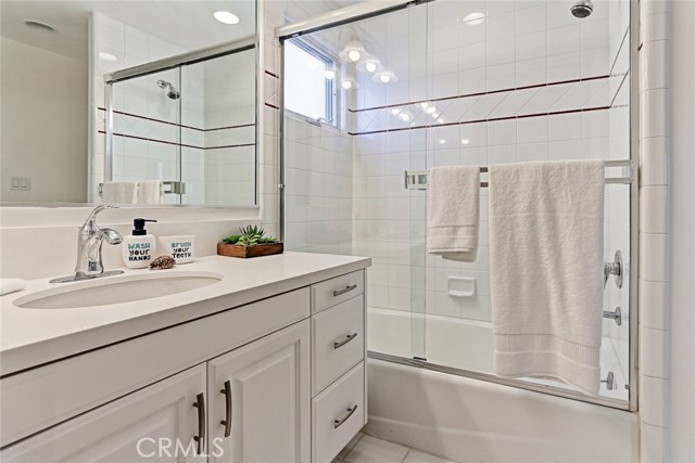 mid level bedroom's ensuite bathroom with a walk in closet, full white quartz slab counters