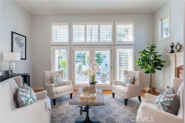 Living room with high ceilings and fireplace, french doors lead to a deck.