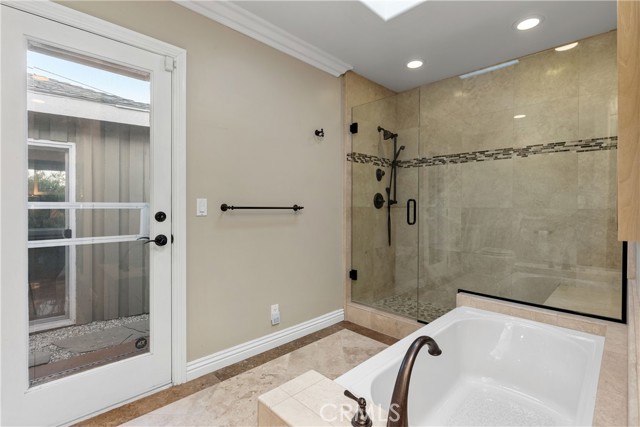 An elegant en-suite bath with gorgeously tiled and frameless oversized shower, soaking tub and the vanity with dual sinks.