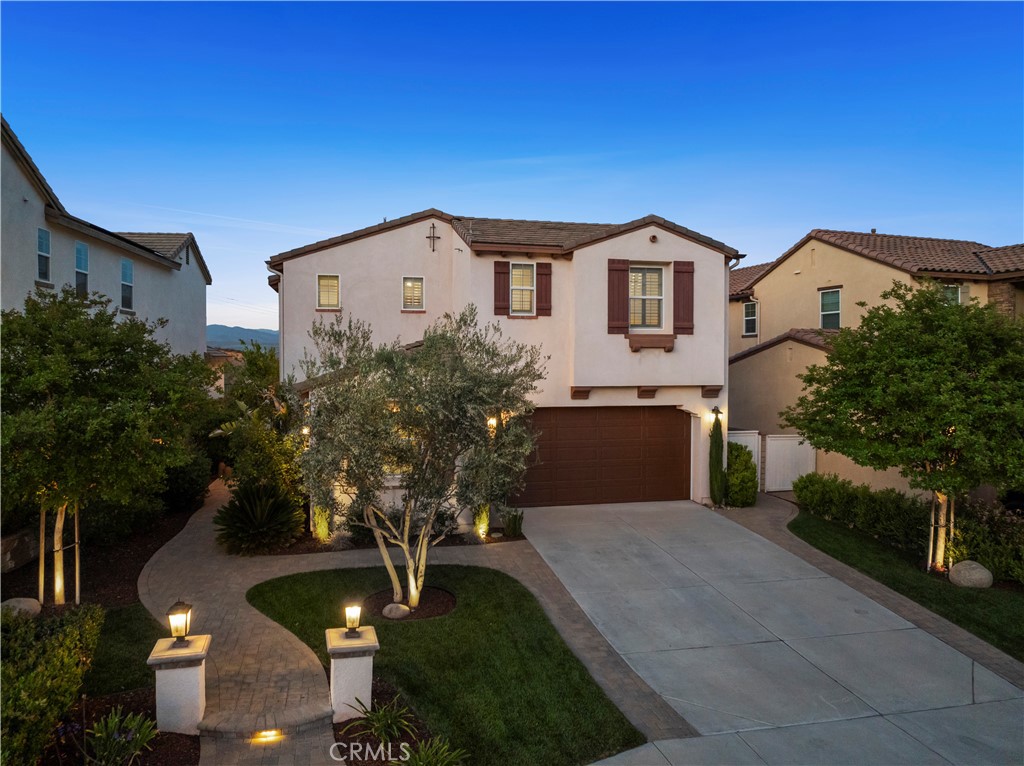 29034 Via Patina Valencia, California Welcome to luxury living behind the gates of West Hills, Valencia. Perched on a quiet street high above the valley in this exclusive gated community, this designer-curated home offers stunning wraparound views of mountain skylines and rolling hills.
Lighted entry pillars greet you along a lush green landscape, with paver walkways that continue to the backyard, creating an elegant and inviting arrival every time you come home.
This model-perfect home offers 4 spacious bedrooms, including a private downstairs Jr. Suite with its own full bath — ideal for guests or multi-gen living — 3.5 beautifully updated bathrooms, and a loft drenched in natural light that could easily convert to a 5th bedroom. Soaring 9-foot ceilings throughout add to the sense of openness and space, while a dramatic lofted staircase opens to the second floor.
Designer upgrades include Restoration Hardware and Pottery Barn light fixtures, engineered wood floors, plantation shutters with window casings, gas fireplace, keyless entry, tankless water heater, dual-zone HVAC and solar.
The kitchen boasts stainless appliances, oversized eat-in island, pantry, classic subway tile backsplash, and oversized glass designer pendants. The separate dining area features crown moulding and scenic views.
The primary suite offers a luxurious retreat, featuring a remodeled bathroom with dual Pottery Barn vanities, a soaking tub, walk-in shower, and a spacious walk-in closet. An additional retreat area, perfect for a home office or gym, opens to a private balcony with expansive valley views.
Secondary bedrooms are generously sized and share a dual vanity bathroom. There’s no shortage of storage: a walk-in linen closet, walk-in hall closet, upstairs laundry room with cabinetry, and built-ins throughout.
Step into your private backyard retreat, where pristine turf, paver pathways, blooming jasmine, a fruiting lemon tree, and high brick privacy walls create a peaceful escape overlooking the valley. As night falls, bistro lights cast a warm glow while city lights twinkle across the distant hills — the perfect setting for entertaining or simply unwinding under the stars.
The two-car garage is immaculate with tiered heavy duty overhead storage.
All this, plus access to miles of walking trails, resort-style pools, parks, playgrounds, shopping, dining, and award-winning schools.
Bring your family, your furry friends, and come make unforgettable memories! Welcome home.