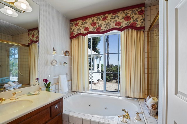 Jetted tub in the primary bathroom has a view of the backyard and gazebo