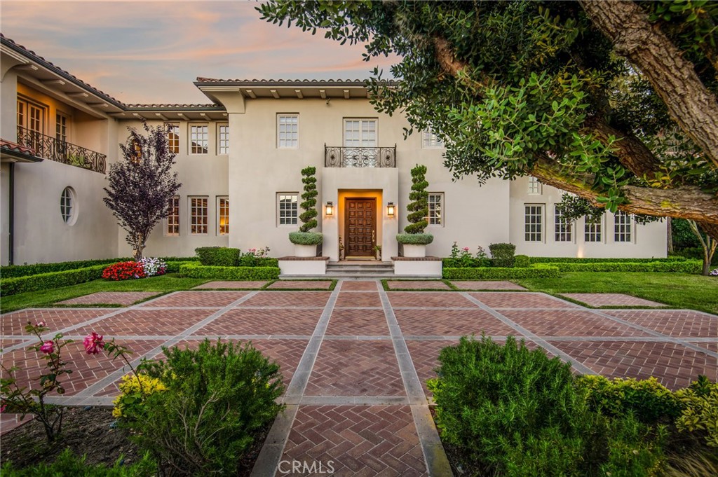 Sited on an over one-and-a-quarter acre lot in the exclusive, guard-gated Bear Brand Ranch community, this Ed Lohrbach-designed estate offers the pinnacle of elegant living. Exuding timeless appeal, the property is a prime example of stately Pasadena-style architecture, with classically scaled interiors and refined sprawling grounds. A soaring double-height foyer with a curved grandeur staircase sets the tone of sophistication prevalent throughout this home. The first floor encompasses formal as well as informal gathering spaces: a dining room, a study, and a sitting room with a magnificent fireplace. A more casual living section opens up to the kitchen with a center island and features sweeping views of the rear yard. The expansive outdoor space offers patios with seating, a pool area with a spa, and elegant meandering pathways set amongst pristine mature landscaping. Grand interiors include four well-proportioned ensuite bedrooms on the upper level, including a sumptuous primary retreat with sweeping views, a sitting area, a fireplace, and a large balcony. Private guest quarters currently utilized as a home office can be accessed via a breezeway, offering seclusion in a multifunctional space. The estate’s sixth bedroom is conveniently located on the ground floor. Impeccable design is evident throughout the stately interiors, with classic millwork, coffered ceilings, and mullioned windows. Exquisitely appointed and located in one of the most coveted enclaves of Orange County, 2 O Hill Ridge presents a truly timeless opportunity.