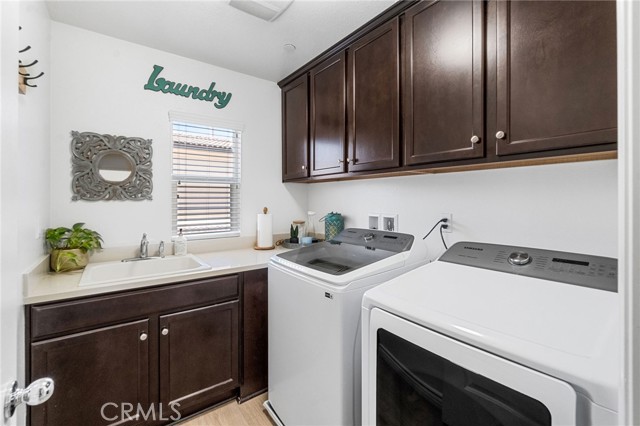 Fabulous upstairs laundry room with sink, built in cabinets, counter and luxury vinyl plank flooring.