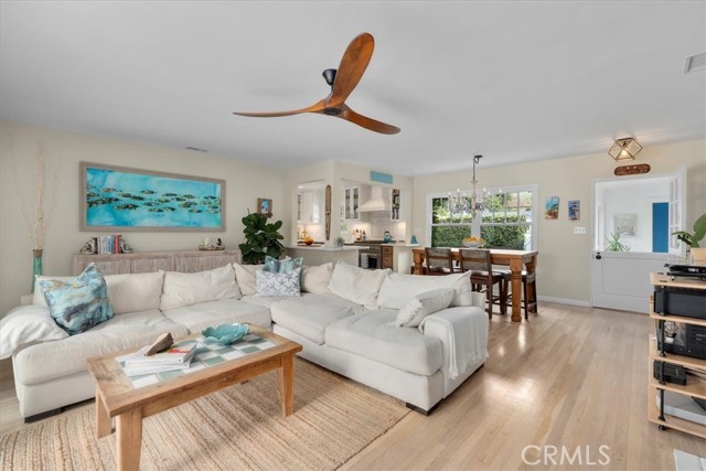 View of the living room, dining area and kitchen from the other wall. Ceiling fan and big windows and doors for airflow