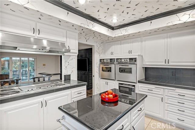 The spacious kitchen features double ovens, granite top kitchen island, ample counter space, and writing desk.