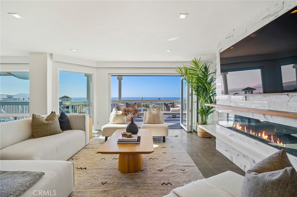 Experience the epitome of coastal luxury in this stunning Dana Point townhome, where panoramic ocean and whitewater ocean views take center stage from both interior and exterior living spaces. Recently upgraded and remodeled, this home features today’s most sought-after finishes and design elements. Two ocean-view balconies extend the living space outdoors, complementing the three-bedroom, three-bath layout spread over approximately 2,300 square feet. Flooded with natural light, the residence boasts an open-concept great room with a fold-away glass door opening to a balcony, enhancing the indoor-outdoor flow. This space is perfect for entertaining, complete with  a stacked-marble accent wall, a linear fireplace, and remote-controlled window blinds. The kitchen is a chef’s dream, outfitted with beautiful countertops, a large butcher-block island, a sit-down bar, custom-designed soft-close maple cabinetry, and top-tier appliances including a Bosch dishwasher, Thermador refrigerator, and Miele steam oven, espresso station, and induction cooktop. The primary suite is a private retreat, crowned with soaring ceilings and featuring a large walk-in closet, an expansive ocean-view balcony with a designer surround linear fireplace, and a spa-like bath with dual vanities, a soaking tub overlooking the ocean, quartz countertops, and a large shower with stylish tile and a frameless glass enclosure. This exclusive gated community of just 20 townhomes showcases classic Cape Cod architecture and designed by the renowned Mark Singer, a resort-style pool and spa, an elevator to all levels, and secured subterranean parking. Located near Dana Point’s vibrant Lantern District, harbor, shops, restaurants, schools, and abundant hiking and biking trails, this home invites you to live the luxurious coastal lifestyle all year round.