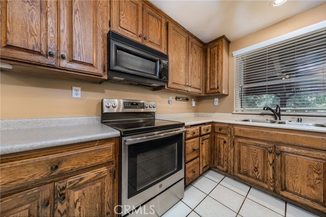 Kitchen with Ceiling Fan, Tile Flooring, Black Appliances & Stainless Refridge