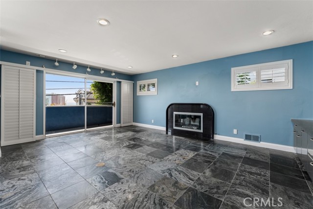 Unit 1 living room with fireplace and a balcony deck with peekaboo ocean views.