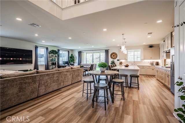 Walking into your great room, you can see the sellers cose to place 2 tables inside. One before the quartz island, and a dining room table in front of your pocket sliding glass doors that open to the patio. Wood laminate floors are easy to clean and beautiful.