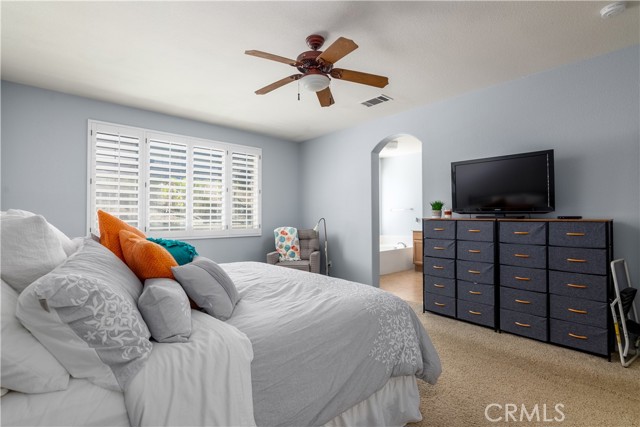 Master bedroom with ceiling fan and plantation shutters.