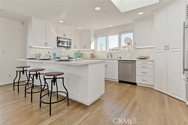 remodeled kitchen with white matte finish subway tiles, white and grey speckled quartz slab counters, walk in pantry, subzero refrigerator, new dishwasher, seating can easily accommodate 4 chairs