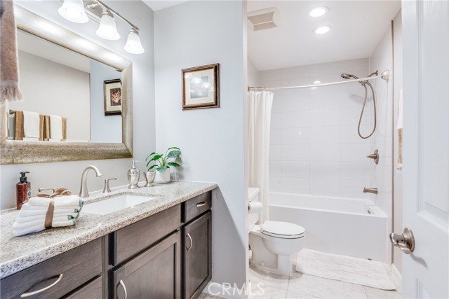 Guest bath featuring granite countertops, dark cabinetry, shower tub combo, and more