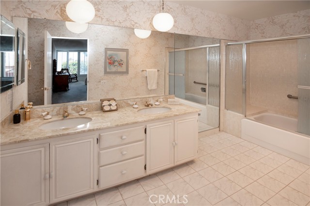 Double sinks in master bath with shelving and shower in tub