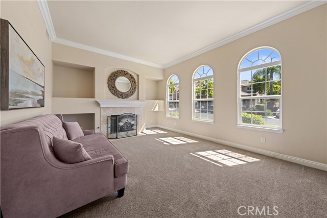 Formal living room with marble faced fireplace, art niches, crowns, tall baseboards & arch windows to allow ample light.
