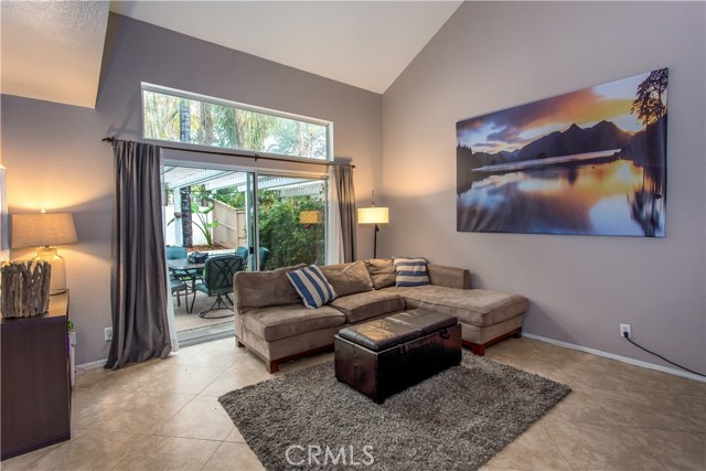 Elegant living room with gas burning fireplace, 2 story ceilings, ceramic tile floors and sliding glass door leading to a perfect backyard.