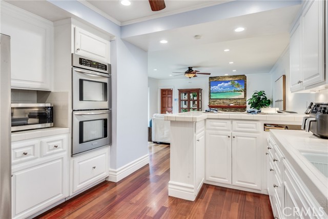 Kitchen with a coastal inspiration offers breakfast bar, white shaker cabinets, stainless appliances and hardwood floors