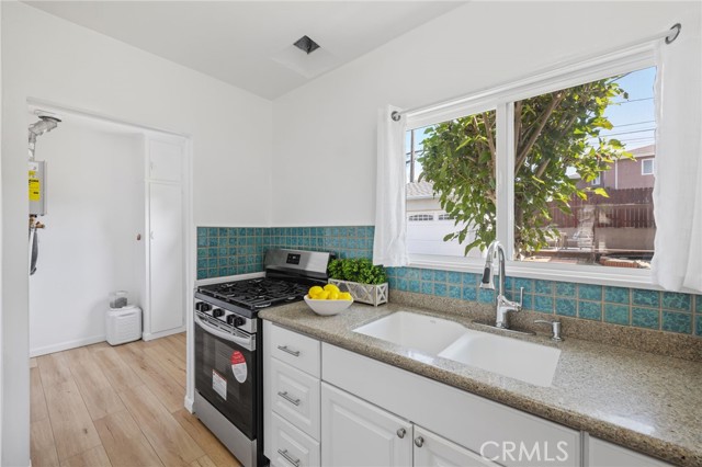 Kitchen with brand new stove, with adjacent laundry area and back door to enclosed yard.