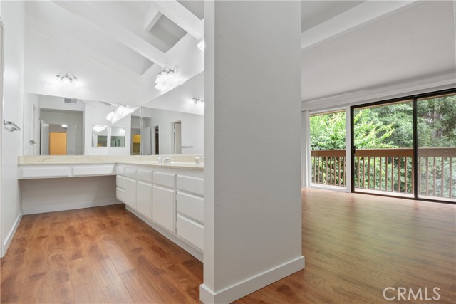 Upstairs primary dressing room with  double sinks, newly installed laminate flooring, and cathedral ceilings