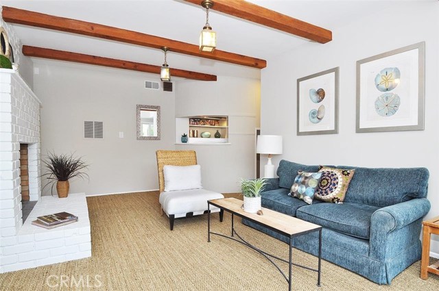 This third living space downstairs boasts seagrass carpet, exposed wood beams, built ins, and opens to the outdoor living space.