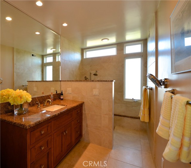 Warm and inviting master bath with a walk in shower is appointed with warm wood cabinetry and granite along with plenty of natural light.