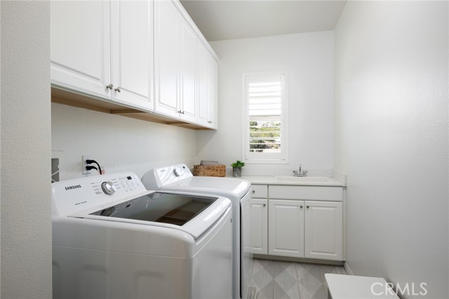 UPstairs laundry with storage cabinets, sink and room to fold