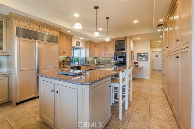 The kitchen includes a Sub-Zero refrigerator plus a warming drawer within the large island.