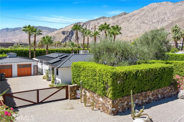 A bohemian-modern retreat steps from downtown Palm Springs, this sprawling 3-bedroom, 3.5-bath ranch sits on landscaped grounds in the Movie Colony district,just a 10-minute stroll from restaurants, galleries, and shopping. The home is turnkey and is offered fully furnished. The home opens onto a cozy sitting area with a velvet ottoman facing a decorative fireplace, a unique church pew bench, and a vintage church stained-glass window. A colorful stained-glass chandelier hangs above a 6-seat dining table. Just off this room is a fully-equipped kitchen designed for entertaining, featuring stainless steel appliances, marble countertops and a wine fridge. Beyond the living area is a light-filled living room, which opens onto the expansive outdoor patio through sliding doors. A resort-style, heated swimming pool lies at the center of an impressive, South-facing backyard lined with palm trees and surrounded by a lush, 10-foot privacy wall. Soak in the sun in one of the cozy loungers along one end of the pool, or catch up with friends around on cushioned sitting area around a stone fireplace along the other. In a separate corner, a spacious hot tub with built-in cushions and 18 jets faces a second stone outdoor fireplace and outdoor bar area. Three more sitting areas surround the pool to provide ample room for entertaining, including a 6-seat dining table. With a BBQ grill and 6-seat outdoor dining table, you can enjoy dinner al fresco. Between three spacious bedrooms, Hinshaw Hideaway comfortably sleeps up to 6 guests. Each bedroom, located in a separate corner of the home for privacy. The primary suite, located off the East end of the living area was designed with a loft feel and is styled in rustic, mid-century decor with wood-paneled walls, a king-sized bed and a 50th anniversary Herman Miller Eames rosewood and leather lounge chair and ottoman. This room also has a 55 flat-screen TV and a luxurious bathroom with marble walls and a soaker tub. The suite opens onto the backyard through floor to ceiling pocket doors, steps from a cushioned sitting area shaded by umbrellas. ********