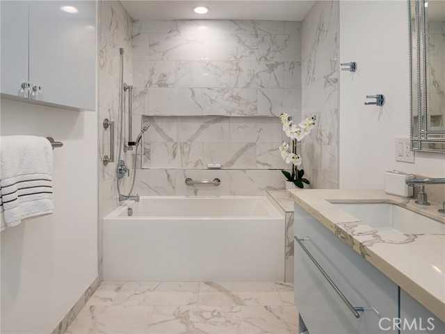 Tub - shower with sliding showerhead, grab bars, in primary bathroom.