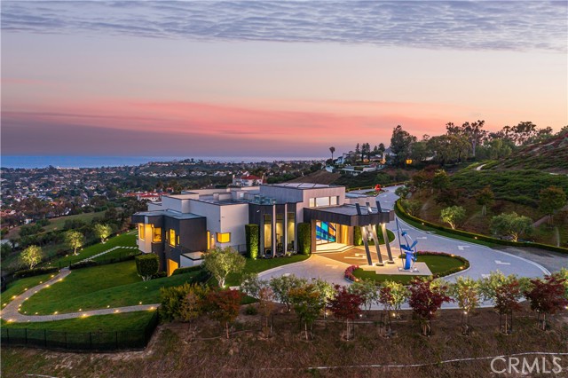 Forged into a mountain, artistically designed on 13.29 sun-kissed panoramic ocean view acres (one of the largest private residential sites in California) this stunning modern architectural legacy estate unites privacy, security, and luxury. Priceless views stretch from Laguna Beach to La Jolla. 
The shimmering Pacific Ocean, city lights and majestic mountains provide a pageant for the eyes and an ever-changing backdrop for living and entertaining. Manicured grounds embrace the estate creating harmony. Enviably set on the largest lot beyond the guarded entry gates of Bear Brand Ranch Custom Estates near Laguna Beach, this hilltop estate is revealed by a massive gate–a work of art comprised of glass and steel providing a tantalizing first impression. The reveal includes an appx. 550-foot ocean view driveway with a circular motor court adorned by two large custom sculptures by noted Laguna Beach artist Jon Seeman. Unmatched in scope, scale and style, the residence welcomes all through a dramatic Porte cochere inspired by The Aria Hotel in Las Vegas. Enter through the award-winning oversized pivot 18' glass and iron entry door that leads to the striking grand entry resplendent with natural light streaming through numerous skylights. Italian modern crystal chandeliers, glass-enclosed elevator, custom exotic stone and stainless-steel finishes and floor-to-ceiling Fleetwood doors and windows throughout adorn the residence like a jewel box.  This trophy property features a main floor spa-like master with gym, sauna, retreat, and Pininfarina bathtub. Five additional luxury ensuite bedrooms are on the lower level. Four guest half bathrooms are easily accessible throughout this 15,000 SF plus artistic canvas. The chef-caliber kitchen and gourmet outdoor kitchen are equipped with generous islands, sleek cabinetry and top-of-the-line appliances. Bask in your stingray shaped negative-edge pool with sculptural waterfalls and open-air firepit central seating area accessed by a glass bridge. The twenty-person spa, huge yard, separate fenced dog run, putting greens, gentleman’s farm, massive game room, private art gallery, hidden Tequila tasting room, two story library, and lavish cinema with tiered seating and stage create a one-of-a-kind setting for elaborate gatherings or intimate evenings. Dramatic high ceilings, solar power, full home generator, state-of-the-art security and attached spacious eight-car garage complete this once in a lifetime opportunity.