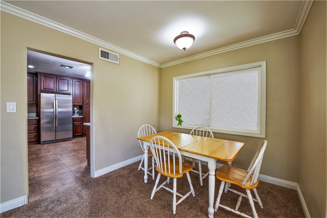 The dining room is next to the kitchen and has a large framed window and crown molding.