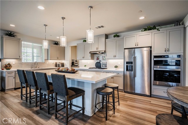 Your chef's kitchen is a show stopper! What a great gathering place! This Great room features the kitchen on one side, with butlers pantry, followed by a walk-in pantry, and opens to the family room. Dolphin grey cupboards with stainless steel hardware. Energy efficient appliances are stainless steel to include a refrigerator, double ovens, 5 burner with hood, dishwasher and farm sink. 10 foot quartz island is the focal point with white quartz that is enhanced with subtle hints of grey adorned with 3 stu...