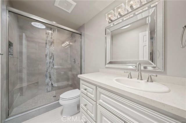 The guest bath is also host to a beautifully remodeled step-in shower with custom inlaid tile details and upgraded fixtures, quartz countertop, and designer mirror and lights.
