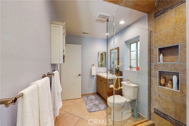 Remodeled upstairs bathroom with rain shower and handheld shower headand rock flooring.