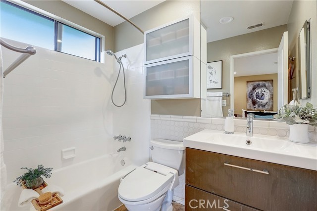 Upstairs Primary Suite bathroom with new modern vanity and bright white shower/bathtub.