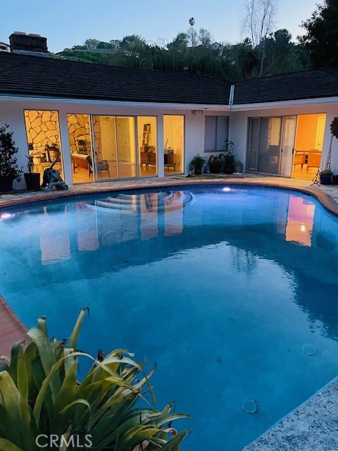 Twilight view of pool and house