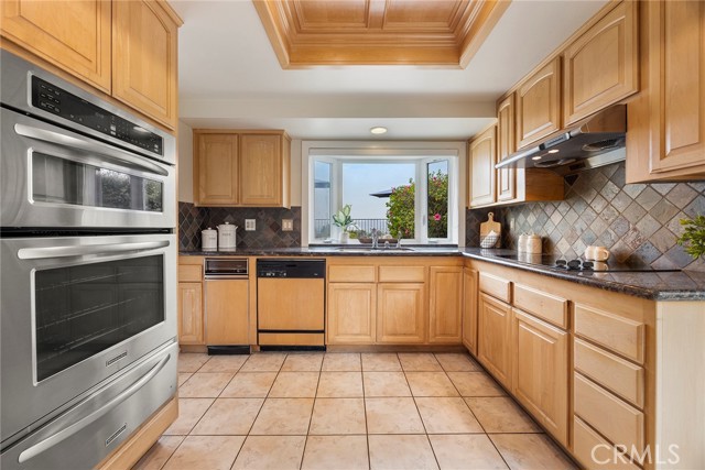 This kitchen features a sleek stainless steel microwave, oven, and a bonus warming drawer below.