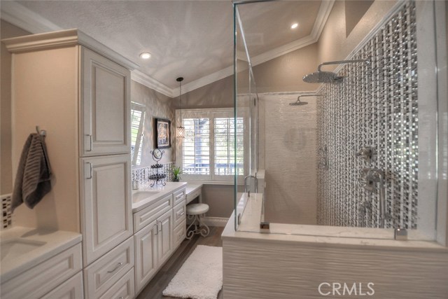 Remodeled spa-like master bathroom with quartz counters dual sinks, two person shower with dual shower heads and designer tile bask splash and shower enclosure, shower wand, and a waterfall feature.