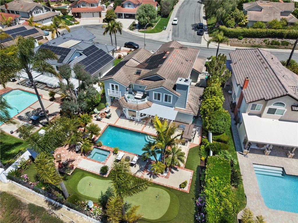 8 Capri Laguna Niguel, California A rare find in one of Laguna Niguel’s most desirable neighborhoods, this Cape Cod-inspired home sits on a south-facing 10,000+ sq. ft. flat lot at the end of a quiet cul-de-sac, offering open canyon and mountain views. Designed for relaxed living and effortless entertaining, the resort-style backyard features a pool and spa, putting green, built-in BBQ with bar seating, covered dining patio, and cozy firepit lounge. Timeless architecture leads to sunlit interiors that blend classic charm with modern comfort, enhanced by the home’s ideal orientation. A welcoming Dutch door entry opens to a spacious layout with hardwood floors, French doors, and large picture windows that bring the outdoors in. The interiors have been customized with architectural details, including arches, tray ceilings, and extensive use of moldings throughout, adding depth and character to each space. At the heart of the home is an expanded kitchen and adjoining family room—perfect for gatherings. The kitchen includes a generous center island, double refrigerator and freezer, gas cooktop, double ovens, walk-in pantry, breakfast nook, and versatile sit-down bar ideal for casual meals or serving buffet-style. The oversized family room impresses with a fireplace, built-in custom cabinetry, an overhead projector and screen, and plenty of space to lounge or host. The floor plan offers flexibility, with a main level bedroom and full bath, plus two oversized guest bedrooms upstairs, a versatile bonus room (ideal as a 5th bedroom, office, media space or playroom), and a spacious primary suite. The primary bedroom includes a spa-style stone enhanced bathroom with soaking tub, a dual sink vanity, custom cabinetry, and two walk-in closets, while the adjoining retreat features a cozy fireplace and access to a private view deck. Additional highlights include a 3-car garage with ample storage + 240 outlet for EV's, cement board siding known for its fire-resistant qualities, and solar pool heating—enhancing efficiency and extending enjoyment of the resort-style outdoor space. The Palisades community is known for its generously sized home sites, low HOA dues, wide streets, and top-tier schools. Residents enjoy easy access to two community pocket parks, a nearby dog park, hiking, and biking trails within the nearby 16.5-acre Chapparosa Park, which provides a direct trail to Salt Creek Beach.