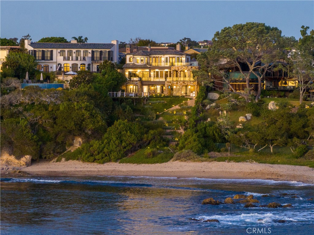 Located on an expansive oceanfront parcel of nearly three-quarters of an acre in the private community of Shorecliffs, this extraordinary residence includes more than 11,000 square feet of living area on four levels. Enveloped by mature seaside gardens, and graced with a private oceanfront pool, this home is among the largest of both oceanfront homes and oceanfront sites in Orange County. Never to be replicated, the house was built from the ground up in 2008 and recently underwent a two-year renovation. The result is a thoughtfully updated interior that features tasteful modern moments integrated into a design that is still warm and inviting. Overall, the house is now light, open and takes full advantage of the breathtaking ocean and cove views. Set above the only private sandy beach in Shorecliffs, the views range from the cove below, to Arch Rock, across to the channel entrance, and finally to Catalina Island on the horizon. From first light in the morning through to sunset, the views are simply stunning. The house itself, never to be approved again under current limitations, provides all the spaces of a proper home – something you will almost never find on the open market here. There is a nearly full-floor master suite with an expansive private oceanfront terrace, sitting room, as well as his and hers baths and dressing areas. Four additional bedroom suites (one in the form of a guest house) complete the private spaces. A formal living room and dining room are complemented by several oceanfront terraces and a private fireside courtyard, a large family room, an impressive home theater, a well-appointed kitchen with breakfast room, a rooftop terrace, a handsome paneled study, and a seaside entertaining level with a gym, bar, and a bonus opening to a large oceanfront terrace with pool. An elevator and an eight-car garage complete the offering. There is also a private pathway to the beach with direct sand access. Set back from the street for maximum privacy, there is little anyone can see of the home from the front exterior. However, once one comes inside a series of impressive spaces unfold as they lead from the four-story entry hall to the oceanfront bluff upon which the home rests. Shorecliffs is situated near to the southern edge of Corona del Mar, though this location enjoys easy walkability to the village and miles of beaches, as well as immediate and unfettered access to the village and all the prized amenities of this area.