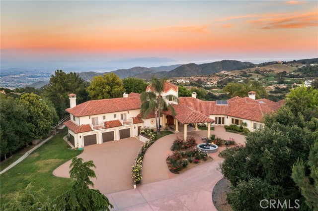 End your quest for the ultimate getaway! Altamira Ranch, a true gentleman's ranch is one of the finest estates of its kind in all of Southern California, with room to relax, play and unwind in virtual privacy while enjoying spectacular views from 21 acres of natural beauty. Adjacent parcels are available (MLS#OC23205513) bringing the total to 57 acres. Located in the prestigious community of La Cresta, this extraordinary estate brilliantly elevates your lifestyle while presenting panoramic, unobstructed, inspiring views of the Temecula Valley, mountain ranges, rolling hills and shimmering lights. Once you've arrived at your private helipad, the adventures begin. Head to the stocked lake for some fishing, ride horses along miles of private roads and trails, host a Santa Maria-style barbecue in the shade of 100-year-old oaks near Bear Creek, or challenge friends on the private pickleball court. Perhaps your plans call for simply kicking back at the estate’s luxurious main house, where 6 en-suite bedrooms and 7 baths are featured in approximately 7400 square feet. Be welcomed by a circular motorcourt with fountain and porte-cochere, the classic early California/Santa Barbara-style residence reveals a stunning 2 story foyer with floating staircase. The home is bathed in natural light and features a massive living room with vaulted open-beam ceiling, floor-to-ceiling windows, formal dining room with bar, family room adjacent to the island kitchen with walk-in pantry, circular nook, and top appliances. Warmed by a cozy fireplace, the main-level primary suite is complemented by magnificent views, a retreat, dual bathrooms including jetted tub, separate shower and walk-in closets. Additional living spaces at the main house encompass 3 en-suite guest bedrooms, a studio/loft, private office plus detached guest house/pool cabana. A natural lagoon-style pool and spa with waterfall and outdoor BBQ offers a backdrop of jaw-dropping views. High quality equestrian facilities include a 2450 sf barn with add'l guest quarters, pastures and round pin. Avocado, citrus and olives trees are abundant in addition to approx 1000 grape vines that have produced award winning wine. 2 wells and a commercial generator takes you "off the grid" if desired. Crowning the majestic Santa Rosa Plateau at 2,100 feet in elevation, Altamira Ranch is cooled by breezes just 21 miles from the ocean. Numerous restaurants, shops and services are close to home, yet the property still feels worlds away