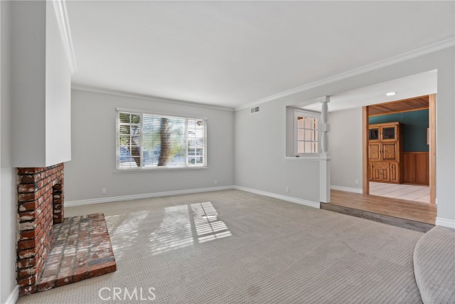 The living room off the front entry has new carpet floors, scraped ceilings, crown moulding and a gas fireplace!