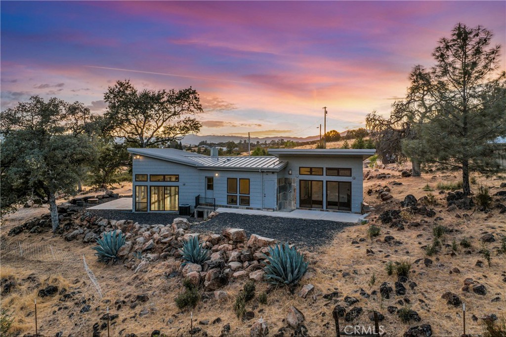 Modern Architect Designed "Rancho" home situated on nearly 5 acres with year-round Putah Creek + Panoramic Mountain & Valley views surrounding!! This 2 bed / 2 bath home offers a spacious 1,736 SF of living space with a functional floorplan that is sure to please. Embrace the natural environment with impressive views & bright light that pours through the expansive windows and skylights throughout. The living area has high vaulted ceilings with recessed lighting, modern ceiling fans and beautifully stained concrete flooring finished with a rustic patische. Large built-in shelving makes for a great library nook or decorative space situated near the new EPA compliant wood burning stove. The chef's kitchen offers a walk-in pantry, 6 burner propane range + hood with tile backsplash, dishwasher, microwave & kegerator. Imported Brazilian countertop in the kitchen provides an artistic touch to the space. 2 spacious bedrooms with modern ceiling fans. The primary has floor to ceiling windows, a propane stove & private patio with tiled outdoor shower. The ensuite primary bathroom has a double sink vanity, walk-in tiled steam shower with 2 benches, multiple shower heads, heated flooring & a speaker! 3 patio areas to enjoy outdoor living year round! Metal roof, concrete siding and interior sprinklers lend to the fire safe nature of this home. 6,500W Generator with hook-up for your convenience! 120v, 220v, & water all available at the driveway pad for RV hook-up or future shop potential! Good producing well! Multiple fruit trees, fenced garden areas and natural rock walls for terracing. Live in the country but enjoy modern conveniences not only in the home but nearby! Located just minutes from local shopping, restaurants, 18 hole golf course, schools and more! There are NO HOA DUES and NO WATER/SEWER BILLS at this home!